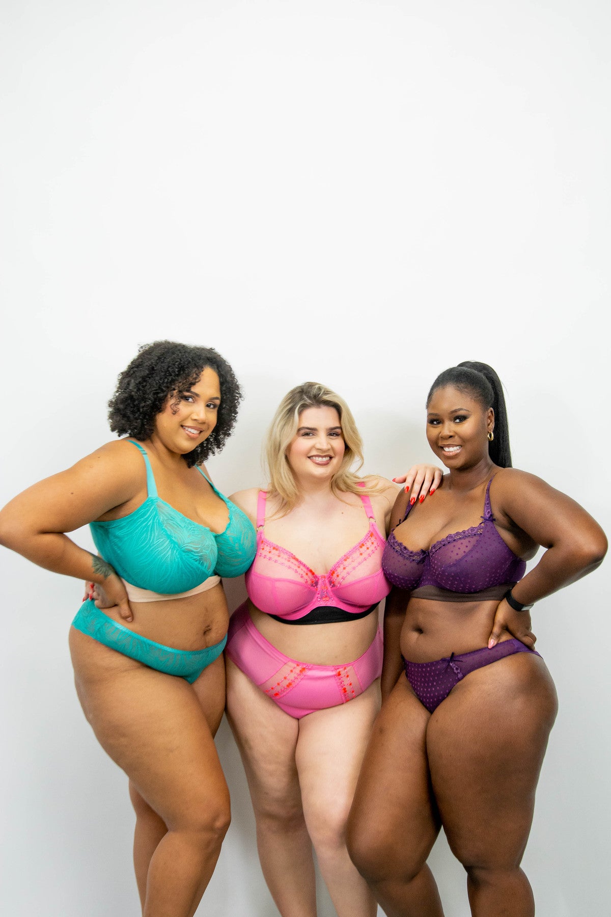 Three models pose confidently wearing the three bra liner colours, beige, black, and brown under their bras